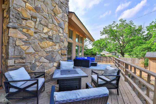 wooden terrace featuring an outdoor living space with a fire pit