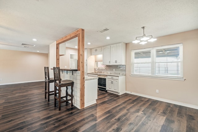 kitchen featuring a textured ceiling, a notable chandelier, white cabinetry, decorative light fixtures, and dark hardwood / wood-style flooring