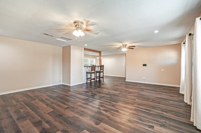 spare room featuring dark wood-style floors, visible vents, baseboards, ceiling fan, and a textured ceiling