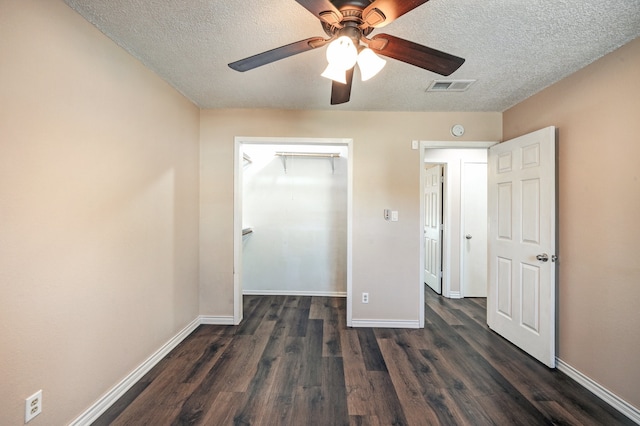 unfurnished bedroom with ceiling fan, a textured ceiling, dark hardwood / wood-style flooring, and a closet