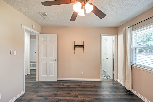 empty room featuring dark wood-style floors, visible vents, and baseboards