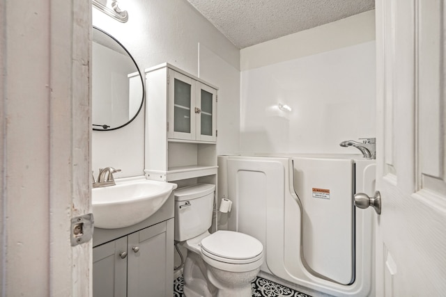 bathroom featuring vanity, a textured ceiling, and toilet