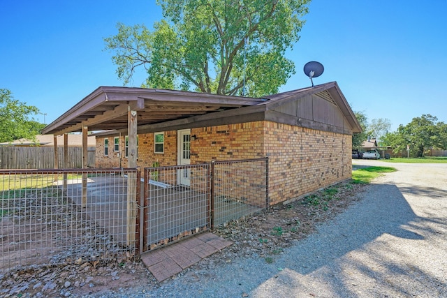 view of home's exterior with fence, brick siding, and driveway