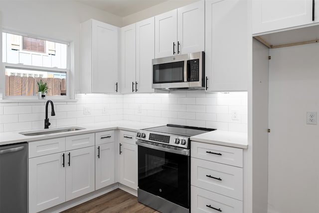 kitchen with white cabinets, sink, decorative backsplash, appliances with stainless steel finishes, and dark hardwood / wood-style flooring