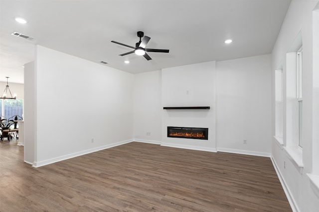 unfurnished living room featuring dark hardwood / wood-style flooring and ceiling fan with notable chandelier