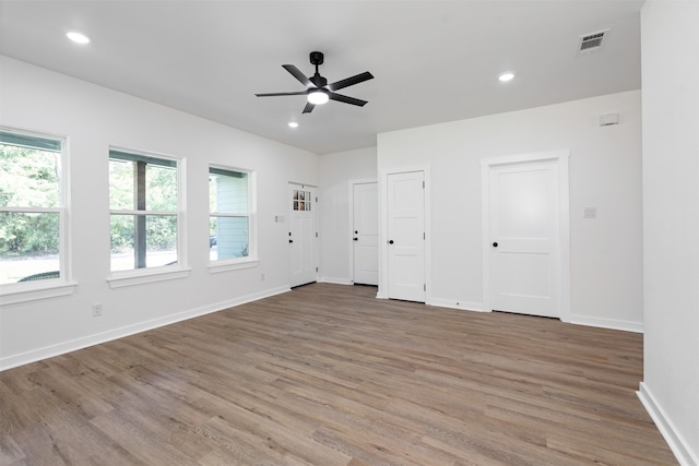 unfurnished bedroom with wood-type flooring, ceiling fan, and multiple closets