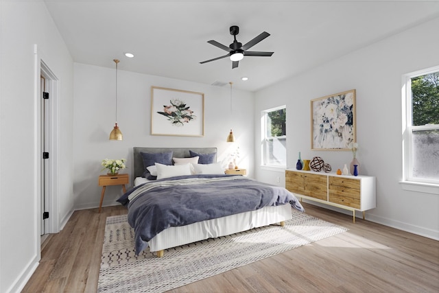 bedroom featuring light hardwood / wood-style floors, multiple windows, and ceiling fan