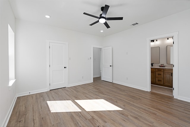 unfurnished bedroom with light wood-type flooring, ensuite bathroom, and ceiling fan