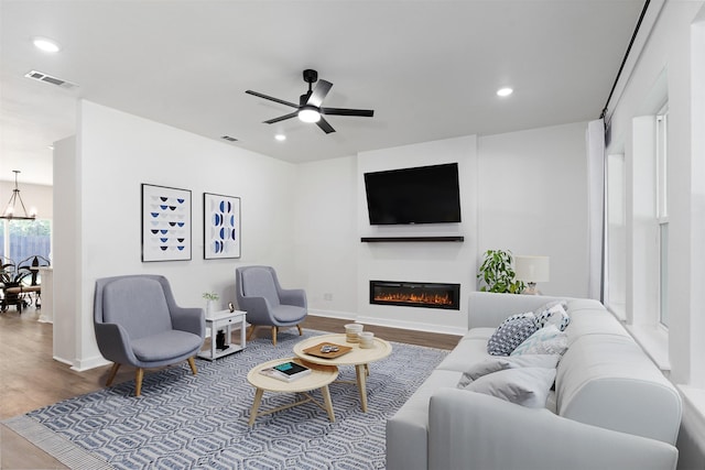 living room with wood-type flooring and ceiling fan with notable chandelier