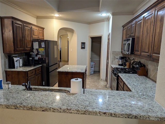 kitchen with light stone countertops, appliances with stainless steel finishes, ornamental molding, and kitchen peninsula