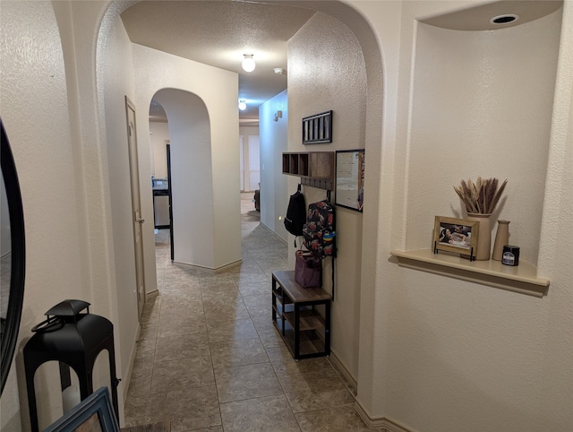 corridor with a textured ceiling and light tile patterned floors