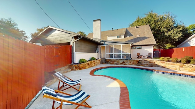 view of pool with a sunroom and a patio area