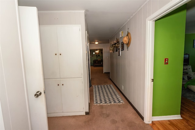 hallway with wooden walls and light hardwood / wood-style floors