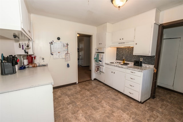 kitchen featuring backsplash, oven, white electric stovetop, and white cabinets