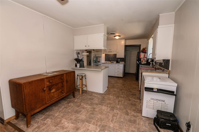 kitchen featuring oven, white cabinets, kitchen peninsula, and tasteful backsplash