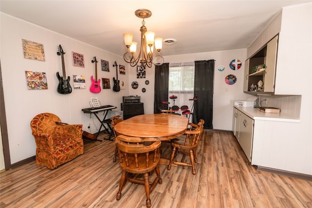 dining area with light hardwood / wood-style floors and an inviting chandelier