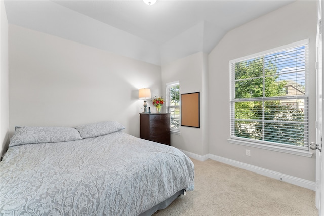 bedroom with multiple windows, lofted ceiling, and light colored carpet