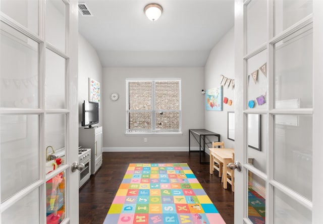 recreation room with lofted ceiling, dark hardwood / wood-style floors, and french doors