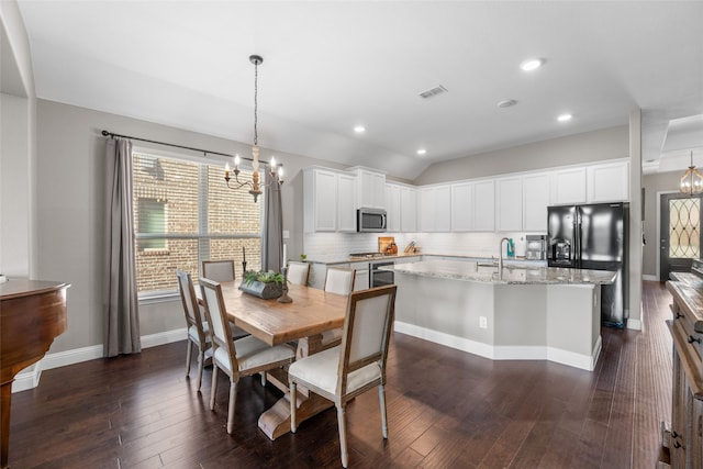 dining room with a notable chandelier, vaulted ceiling, sink, and dark hardwood / wood-style flooring