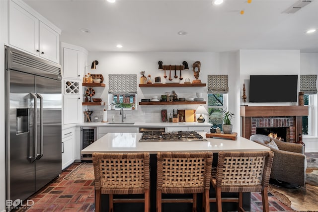 kitchen featuring appliances with stainless steel finishes, wine cooler, white cabinets, a center island, and sink