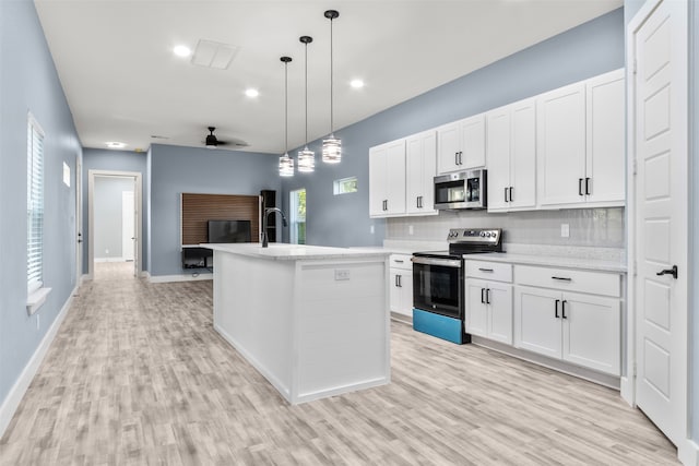 kitchen featuring a center island with sink, appliances with stainless steel finishes, decorative light fixtures, and white cabinets