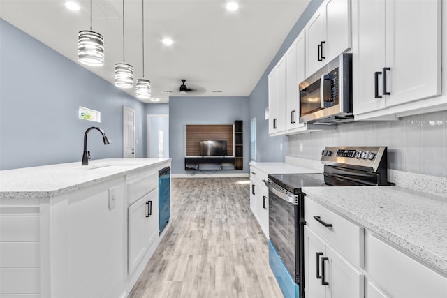 kitchen with appliances with stainless steel finishes, sink, white cabinetry, light hardwood / wood-style floors, and decorative light fixtures