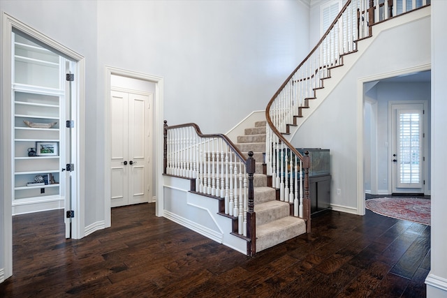 stairway featuring a high ceiling, wood-type flooring, and built in shelves