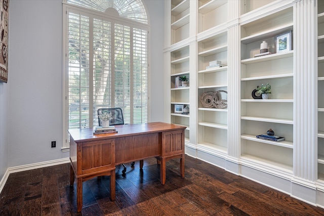 office with built in shelves and dark wood-type flooring