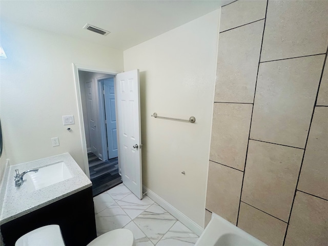 bathroom featuring vanity, a bathing tub, and toilet