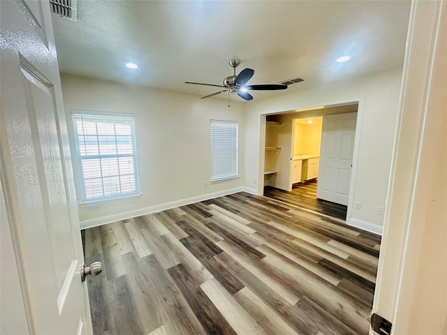 unfurnished bedroom featuring a closet, ceiling fan, a walk in closet, and hardwood / wood-style flooring