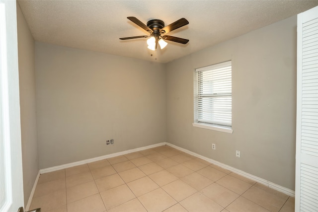 empty room with a textured ceiling, light tile patterned floors, and ceiling fan