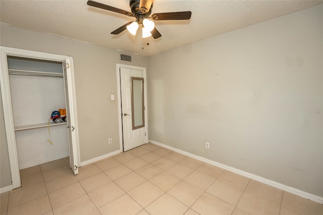 unfurnished bedroom with ceiling fan, a textured ceiling, and light tile patterned floors