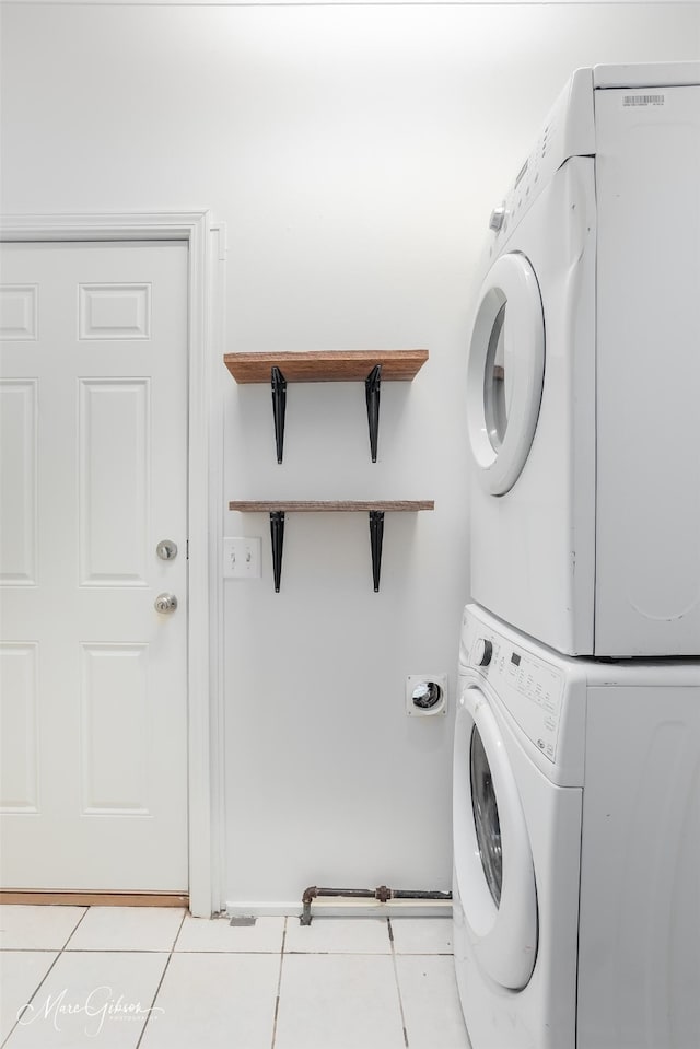 laundry area with light tile patterned flooring and stacked washing maching and dryer