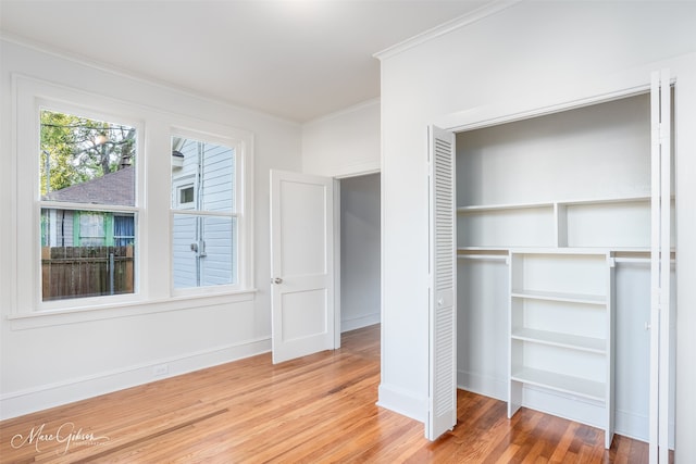 unfurnished bedroom featuring a closet, hardwood / wood-style flooring, and crown molding