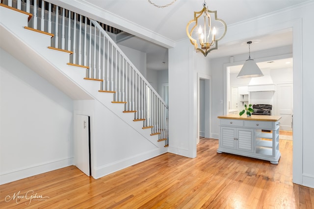 stairway featuring wood-type flooring, a chandelier, and ornamental molding