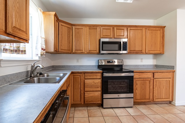 kitchen with appliances with stainless steel finishes, light tile patterned flooring, and sink