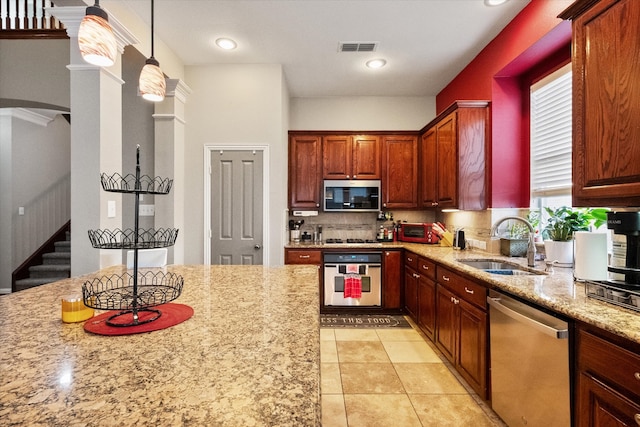 kitchen with appliances with stainless steel finishes, light stone counters, tasteful backsplash, pendant lighting, and sink