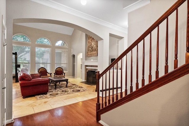 foyer with wood-type flooring, a tiled fireplace, and crown molding