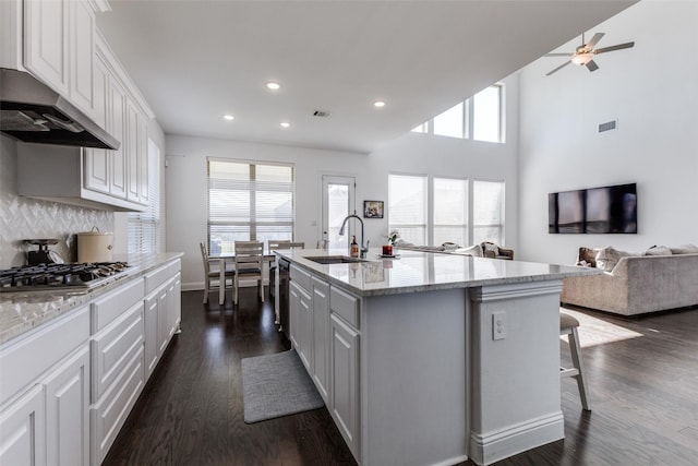 kitchen featuring a kitchen island with sink, sink, white cabinetry, and a breakfast bar