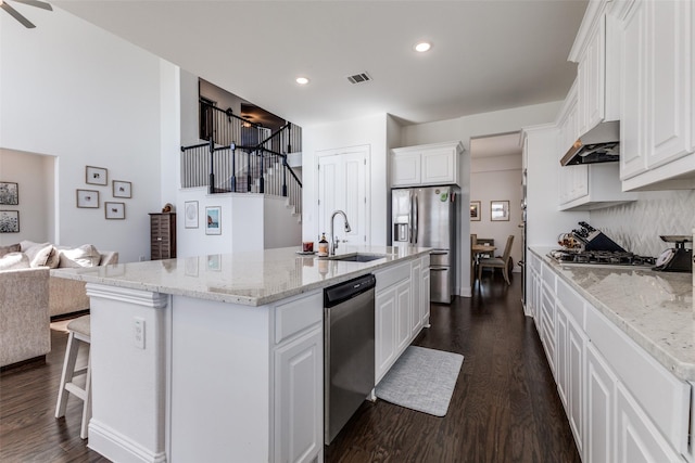 kitchen featuring sink, appliances with stainless steel finishes, white cabinets, and a center island with sink