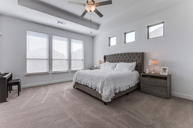 carpeted bedroom with a raised ceiling and ceiling fan