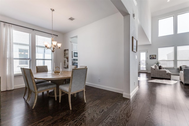 dining room featuring dark wood-type flooring, a chandelier, and plenty of natural light