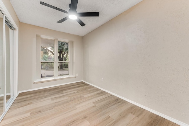 unfurnished room with a textured ceiling, light wood-type flooring, and ceiling fan