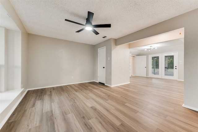 interior space featuring ceiling fan with notable chandelier, light hardwood / wood-style floors, and a textured ceiling