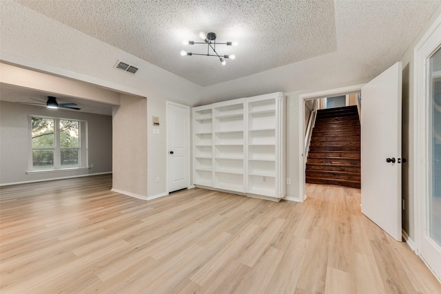 unfurnished bedroom featuring a chandelier, a textured ceiling, and light hardwood / wood-style floors