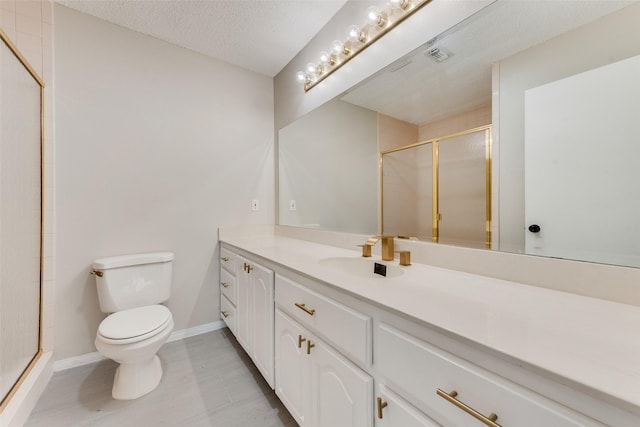 bathroom featuring vanity, a shower with shower door, a textured ceiling, and toilet