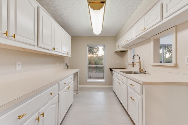 kitchen featuring white cabinets, sink, and a textured ceiling