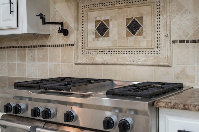 room details with tasteful backsplash, white cabinetry, stove, and stainless steel gas stovetop