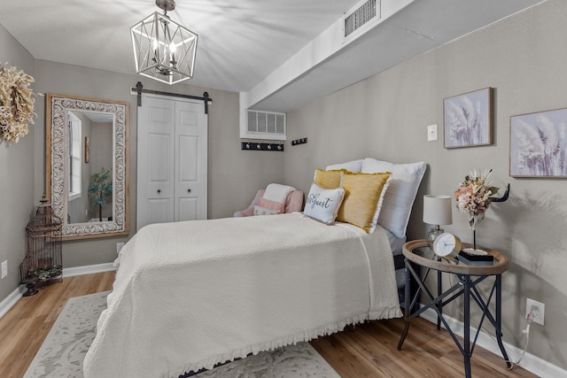 bedroom with a closet, a barn door, and light wood-type flooring