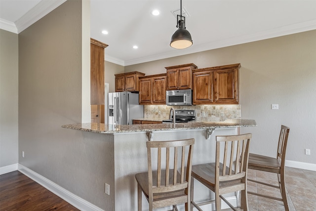 kitchen featuring light stone counters, hanging light fixtures, ornamental molding, kitchen peninsula, and stainless steel appliances